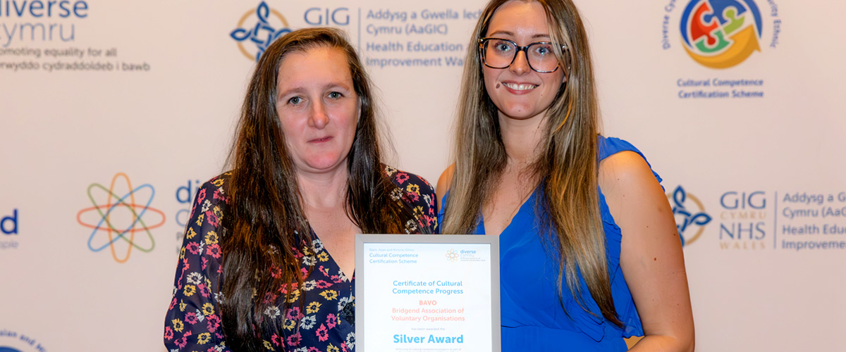 Gail and Laura holding the BAVO SIlver Award certificate against a backdrop of the Awards Night sponsor logos